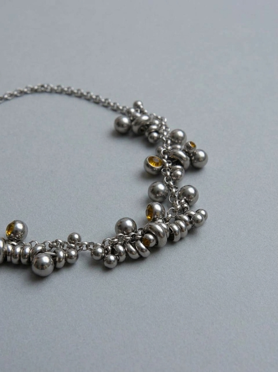 Silver beaded necklace on a light gray background