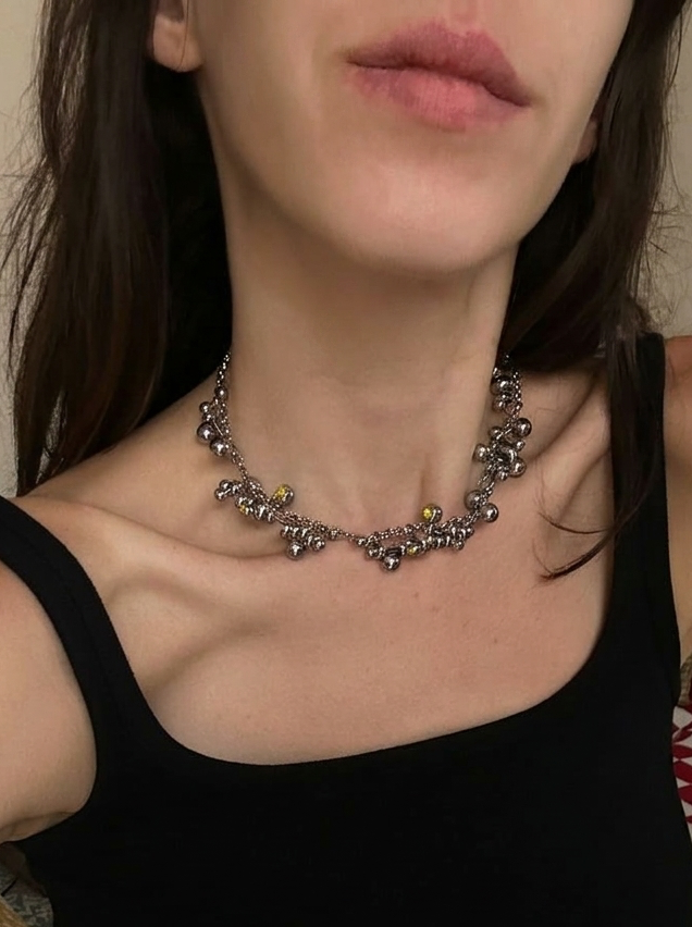 Person wearing a black tank top and a decorative necklace indoors.