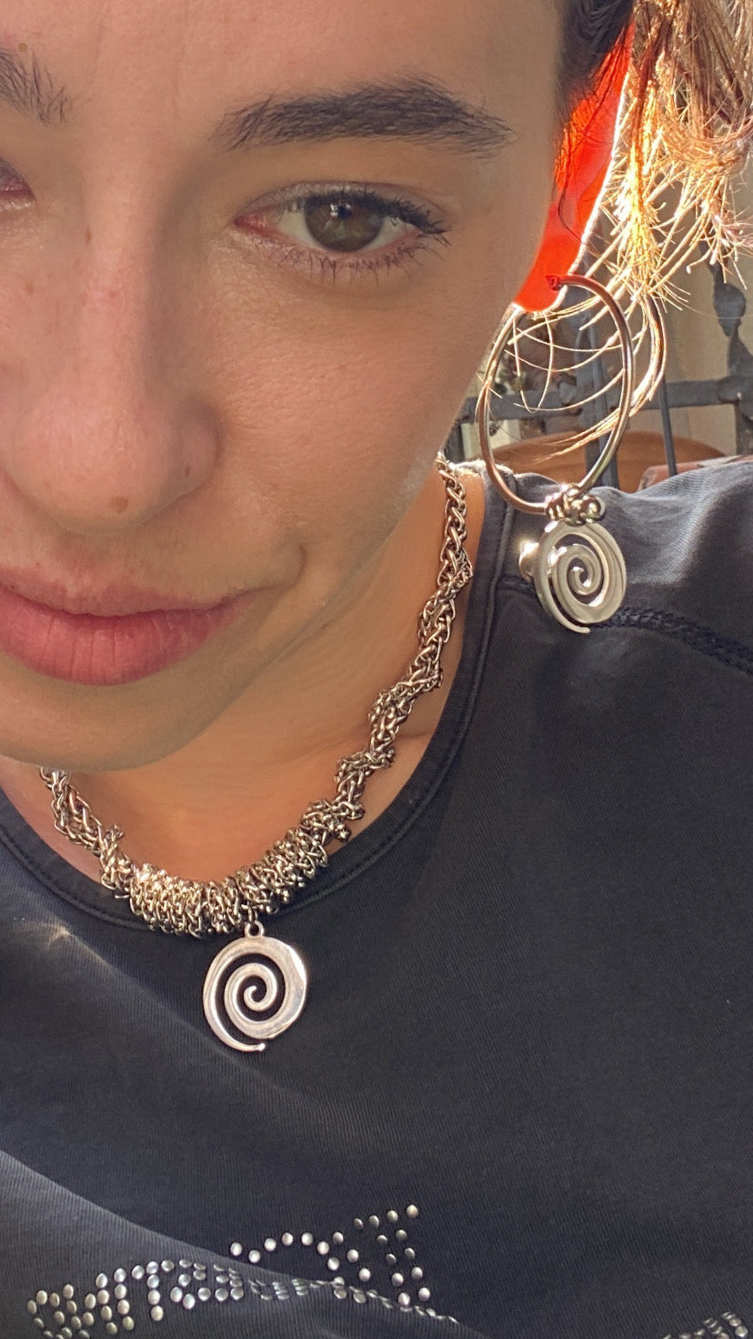 Silver chain necklace with a spiral pendant on a gray background