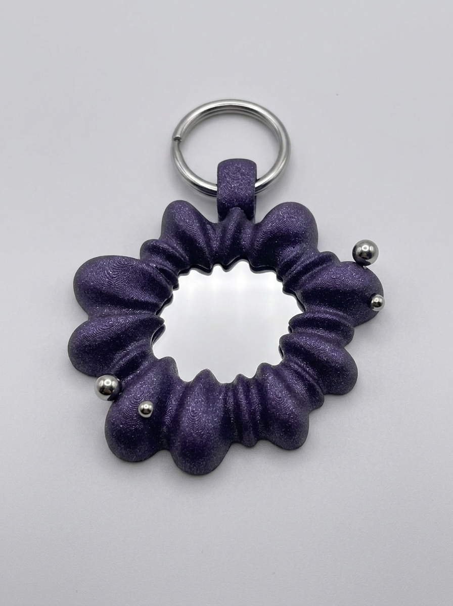 Purple scrunchie keychain with metal beads on a light gray background