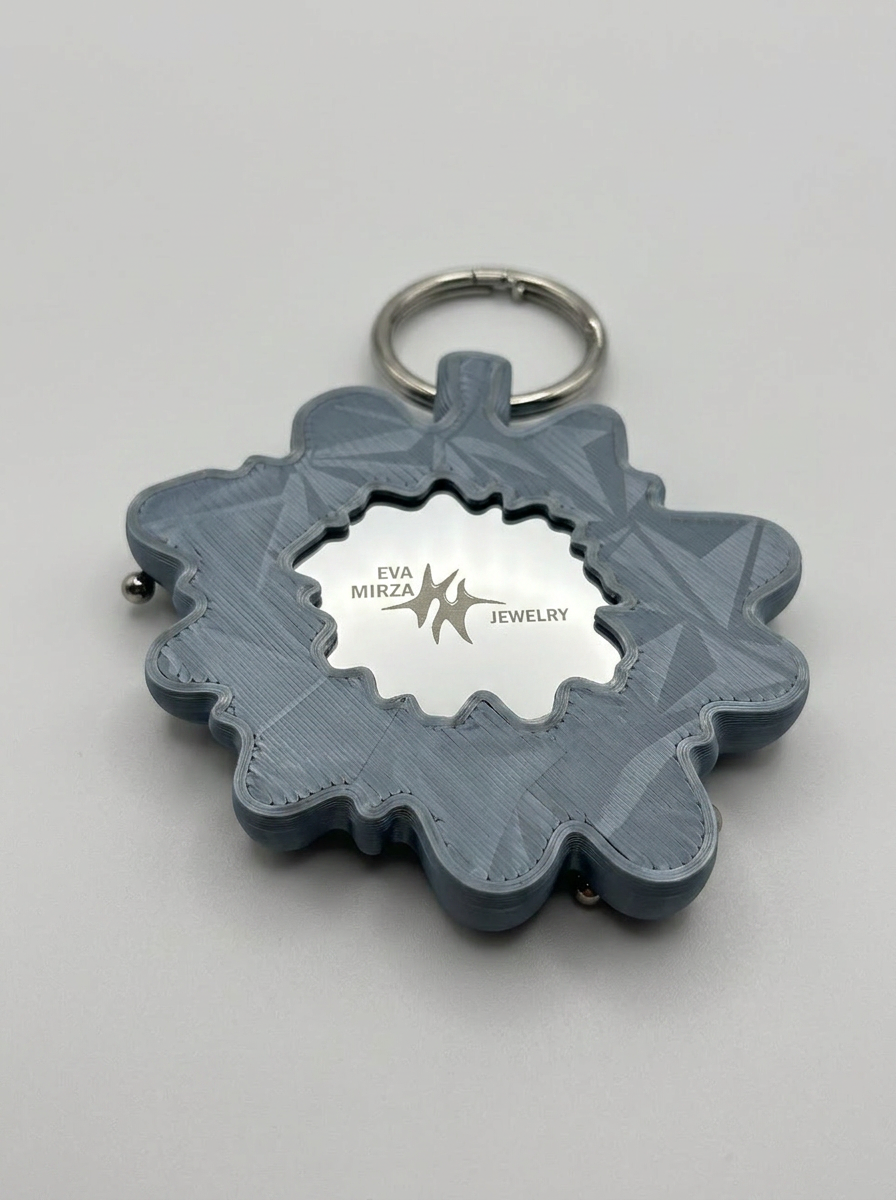 Gray decorative keychain with a brand logo on a light gray background