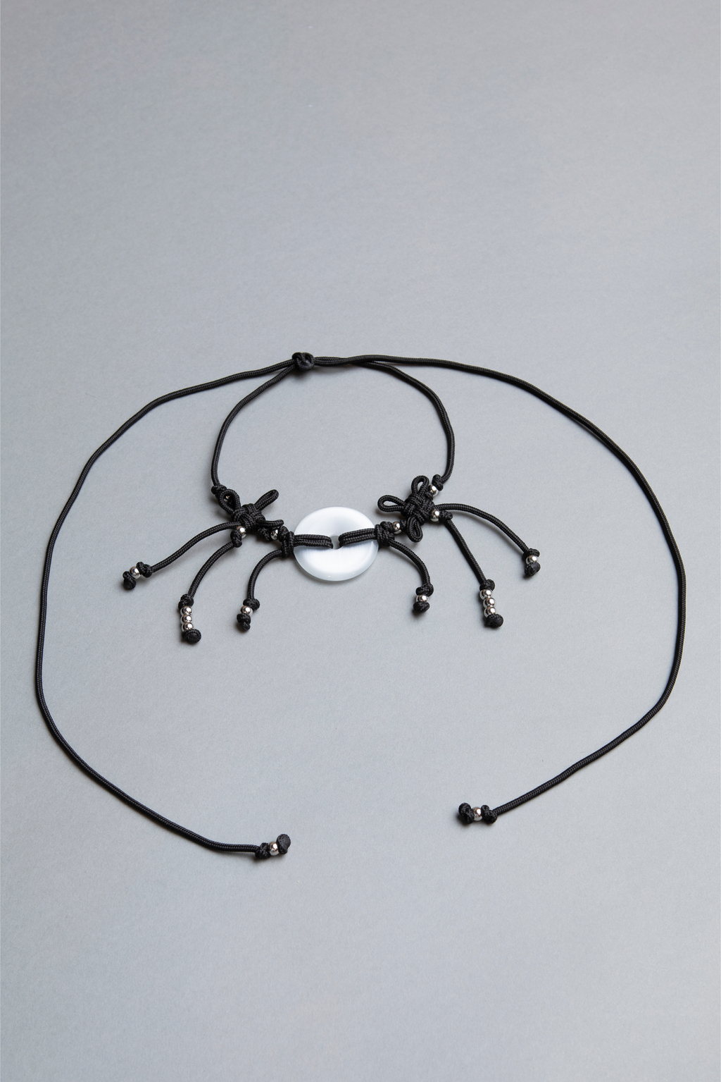 Black spider-shaped necklace on a gray background