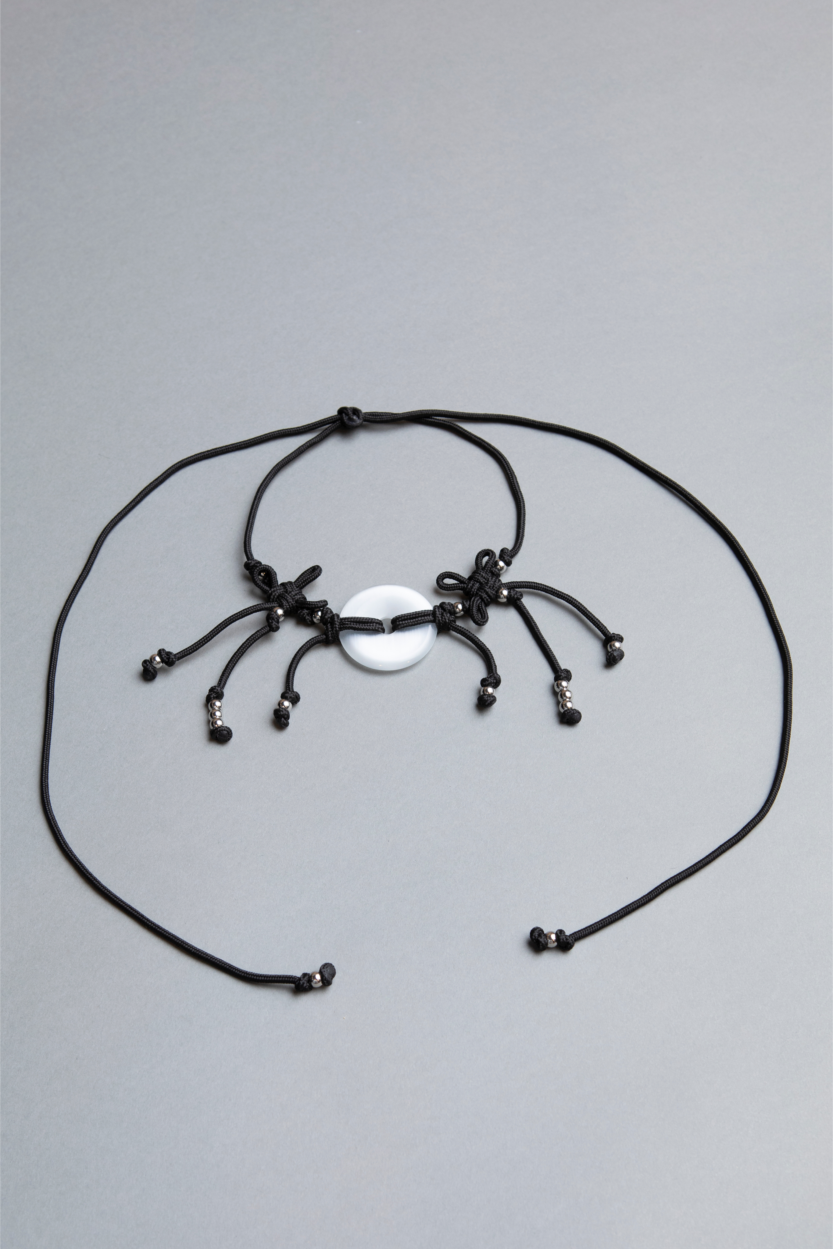 Black spider-shaped necklace on a gray background