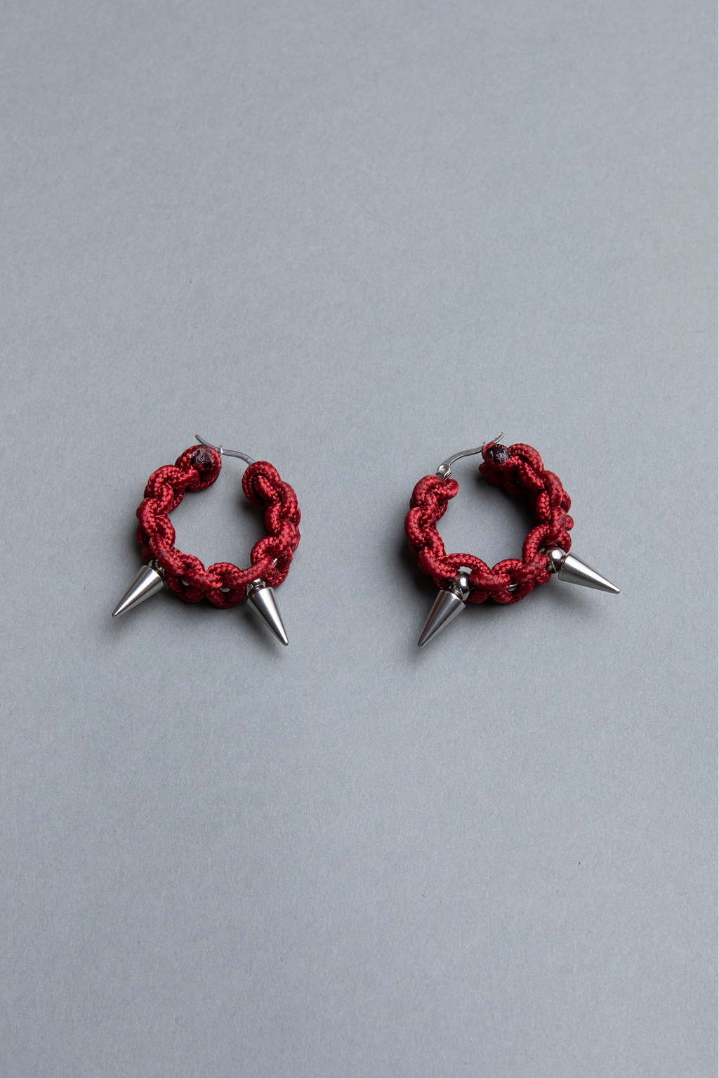 Red hoop earrings with spikes on a gray background