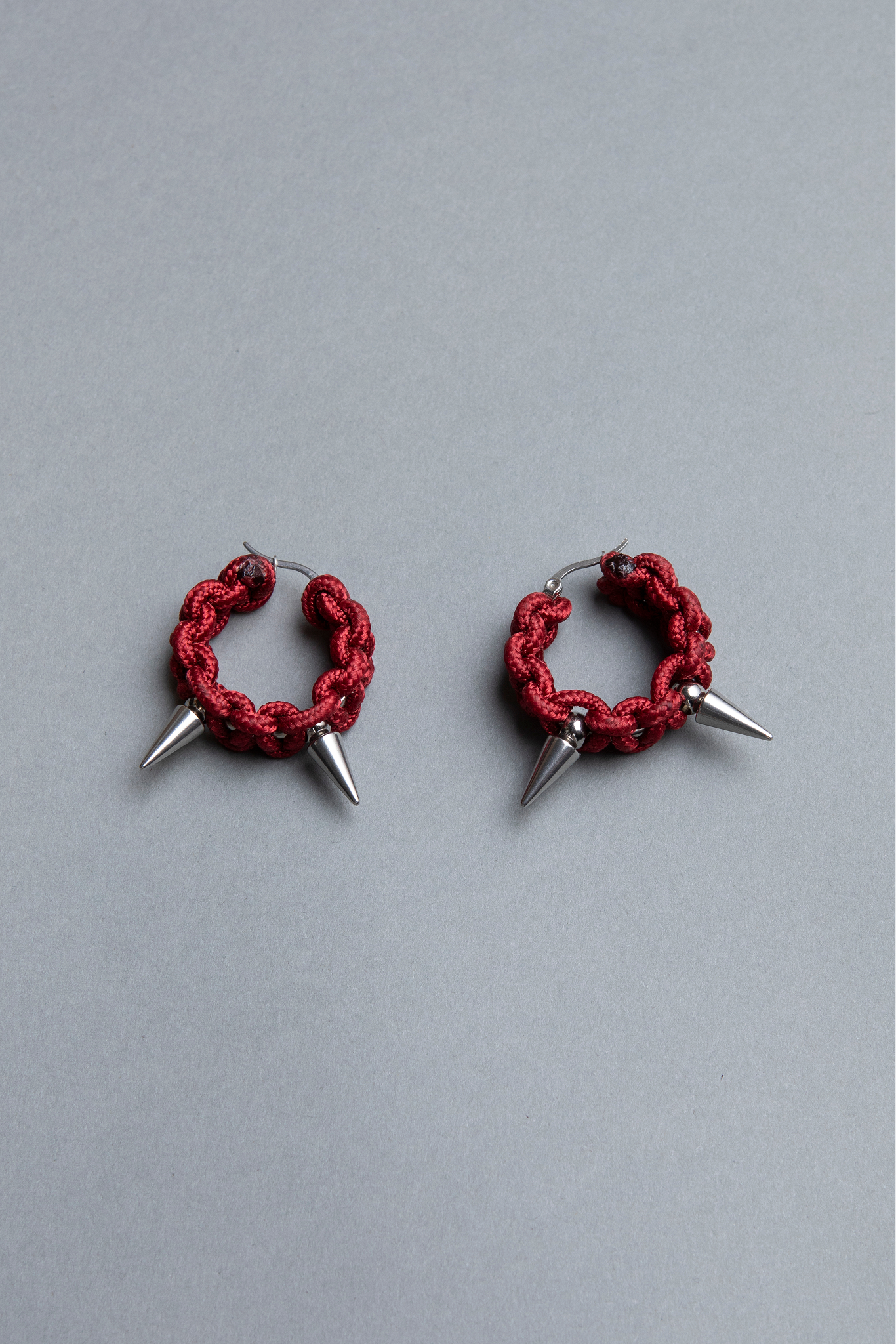 Red hoop earrings with spikes on a gray background