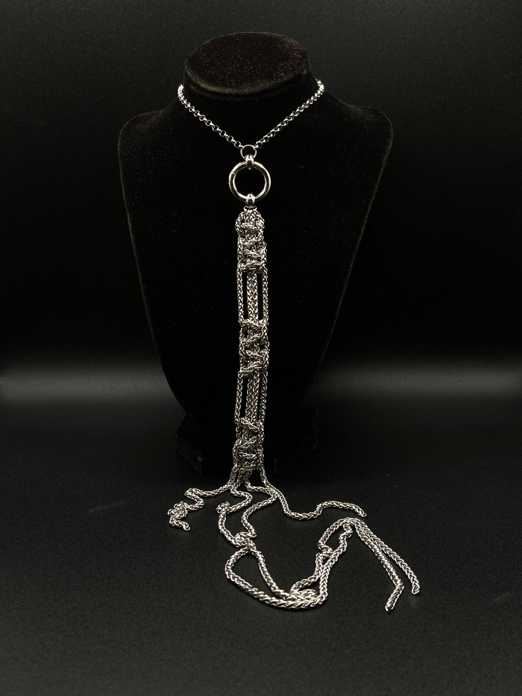 Silver chain necklace on a black mannequin against a black background