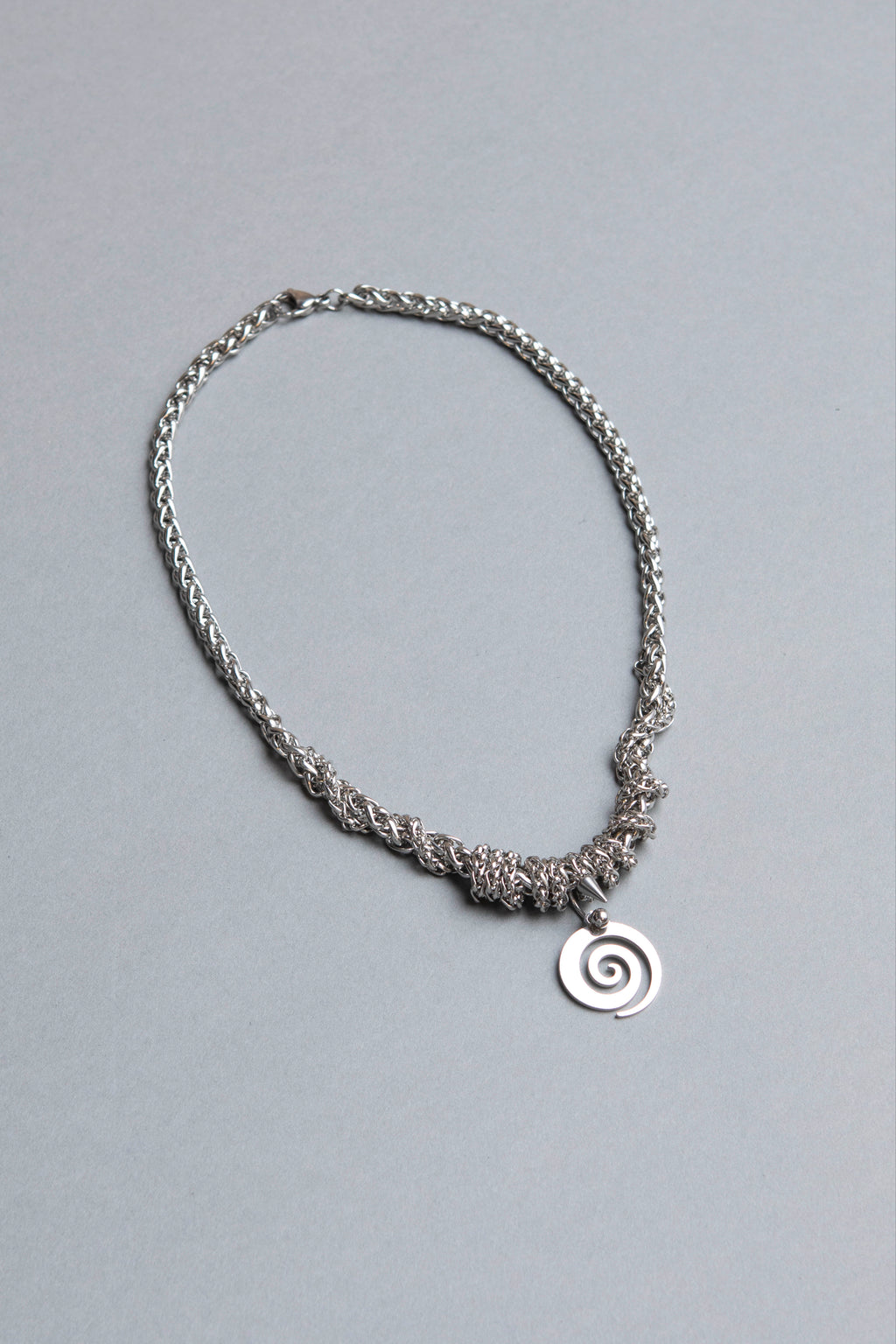 Silver chain necklace with a spiral pendant on a gray background