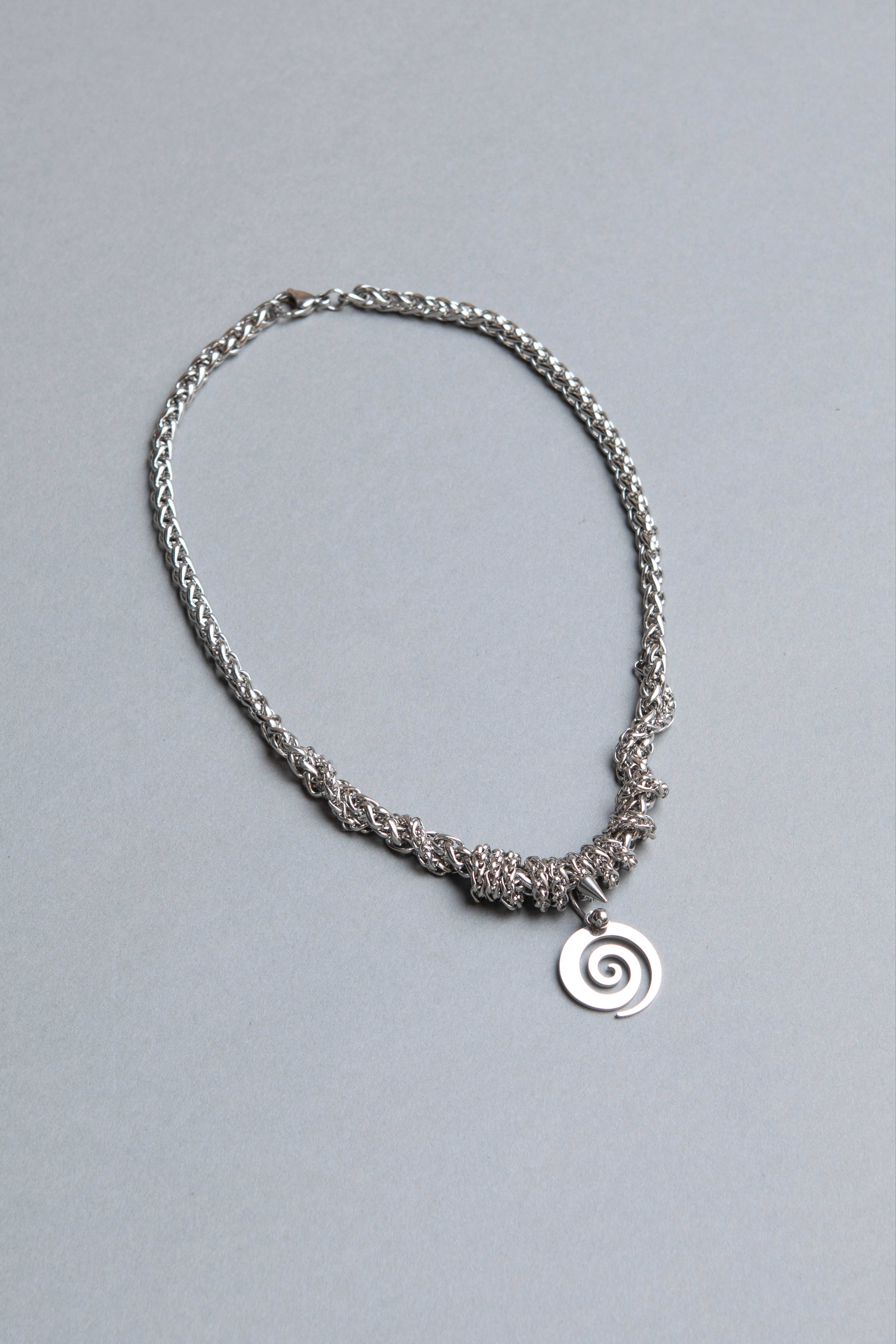 Silver chain necklace with a spiral pendant on a gray background