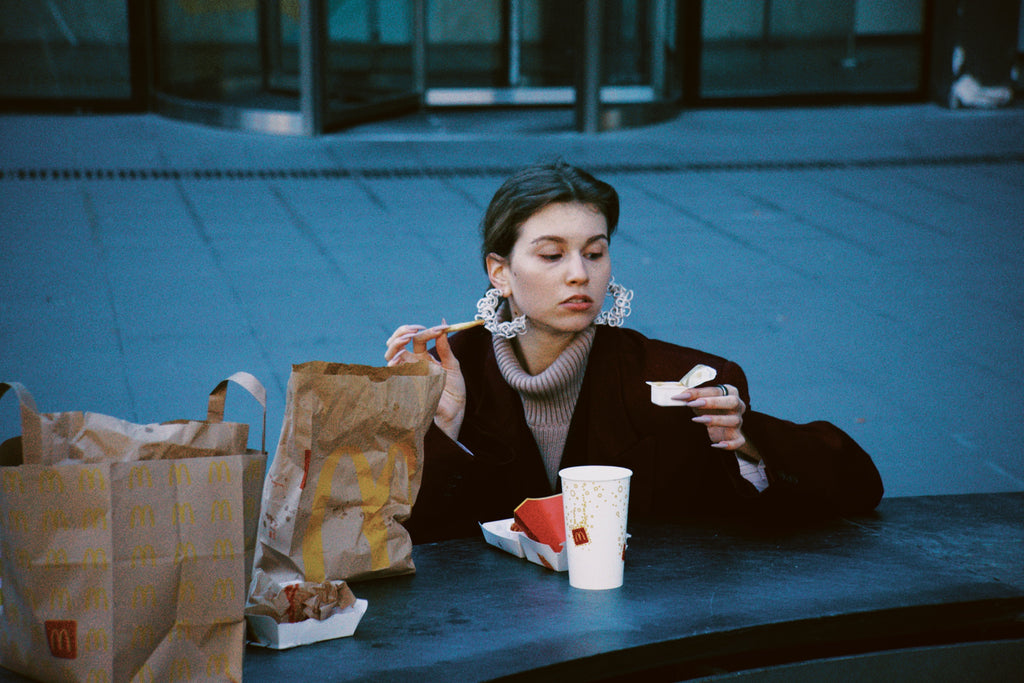 Woman sitting at a table with McDonald's bags and food, looking at her phone.